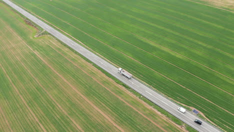 Trucks-and-car-passing-on-a-road-green-grass-field-Spain-agronomy-farmland